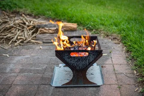 Campfire, fire pit filled with burnt wood and flames. Chopped fire wood in .. Stock Photos