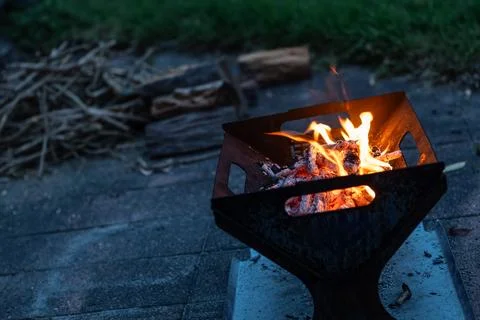 Campfire, fire pit filled with burnt wood and flames. Chopped fire wood in .. Stock Photos