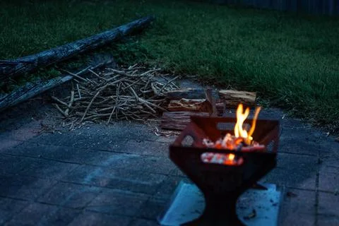 Campfire, fire pit filled with burnt wood and flames. Chopped fire wood in .. Stock Photos