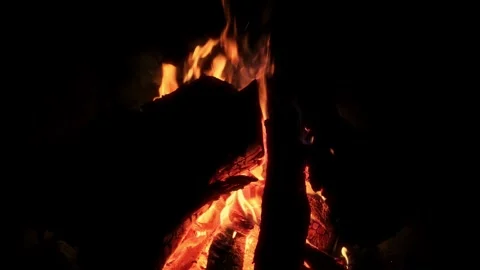 Campfire glow ambiance, Bright flames flicker amidst smoky air creating cozy Stock Footage 325613385