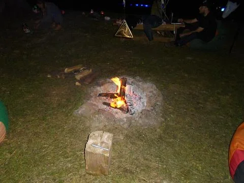 Campfire in open fire pit at night with people and geometric ornament Stock Photos