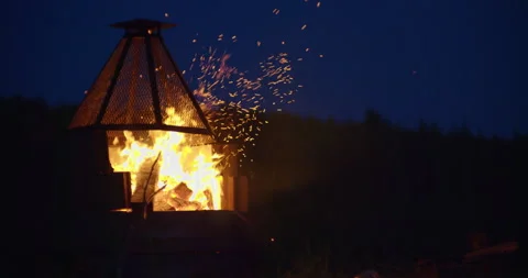 Campfire pit by the lake at night with fire spakles in dark sky / Slow motion Stock Footage 130928330
