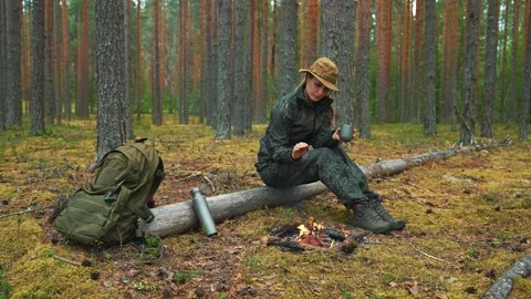 The campfire warms the traveler in the pine forest; the woman enjoys the heat Stockbeeldmateriaal 317234734