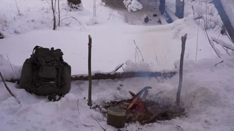 Campfire in the winter forest, next to a backpack and a military bowler Video stock 146572468