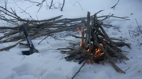 Campfire in winter snow with a hatchet axe in background Stock Footage 121220149