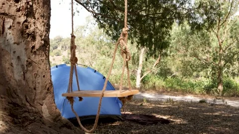 Camping in the countryside with swing in a tree and tent Stock Footage 241252687