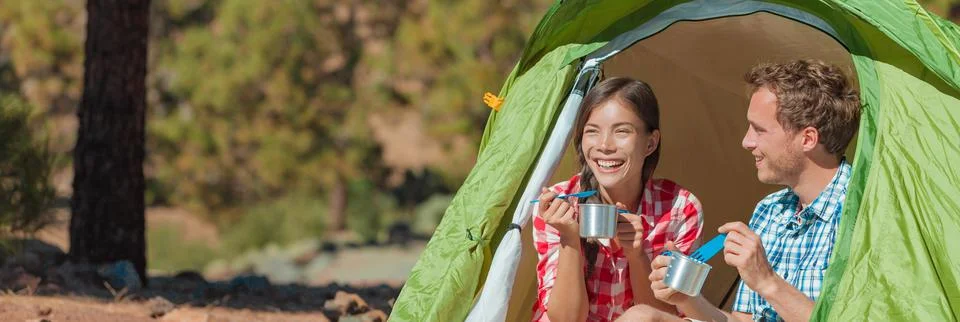 Camping couple eating food in tent on summer travel camp holiday banner Stock Photos