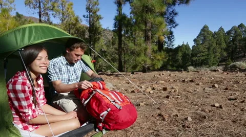 Camping couple in tent talking looking in backpack - campers in forest Stock Footage 42688817