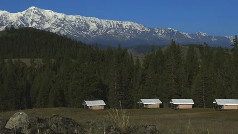 Camping in the forest against the backdrop of snow-capped mountains 4K Stock Footage 123926458