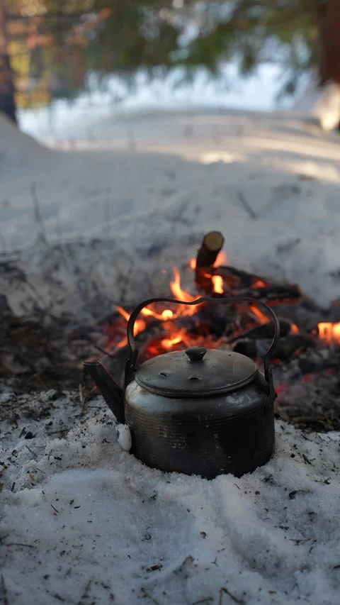 Camping kettle heating on a campfire in a snowy Vídeo Stock 330387756
