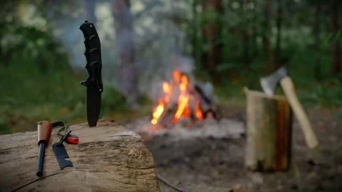Camping knife and fire starter flint on wood log in forest Stock Footage 341878484