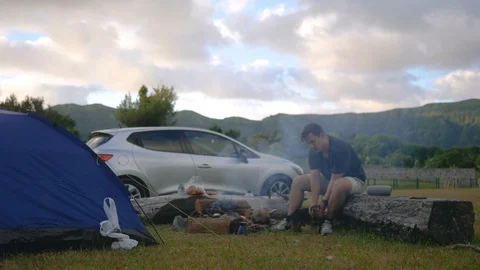 Camping in nature with a fire and a guy playing with a dog on the background of Stock Footage 102293030