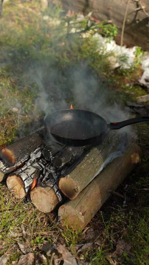 A camping pan is heating up over a campfire. A close-up of the pan warming up on Stockbeeldmateriaal 308289965
