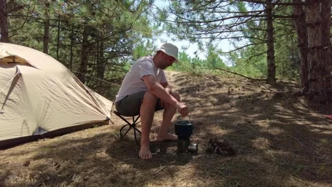 Camping Prep: Man Collecting Pine Cones for Boiling Water by Tent Stock Footage 294766586