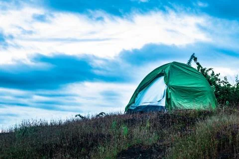 Camping solo at mountain top with dramatic sky at evening 스톡 사진