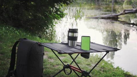 Camping table with thermo cup and smartphone outdoors Stock Footage 194539315