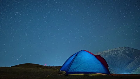 Camping tent in a clearing in the mountains under the starry sky. Time-lapse of Stock Footage 248213672