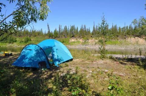 Camping tent on the shore of a mountain river. Stock Photos