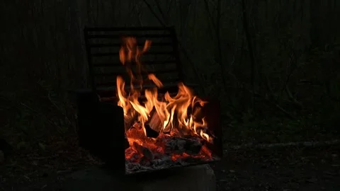 Campsite fire pit with an orange fire burning and crackling with sparks flying i Stock Footage 249559696