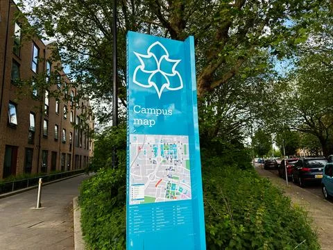 Campus map sign on a tree lined street outside university buildings in Manc.. Stock Photos