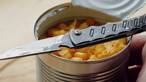 A can of corn opened with a small mild steel pocket knife. Survival tools  Stock Footage 276459338