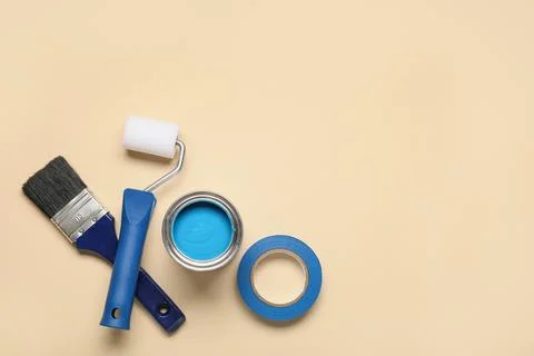 Can of paint with brush, roller and adhesive tape roll on beige background Stock-Fotos