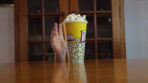 Can of popcorn that a mischievous hand knocks down and falls quickly on the tabl Stock Footage 139032682