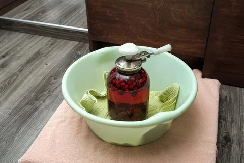 A Can Seamer. Canning cherry compote using a manual seaming machine to seal a Stock Photos