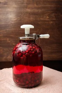A Can Seamer. Canning cherry compote using a manual seaming machine to seal a Stock Photos