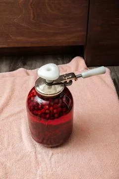 A Can Seamer. Canning cherry compote using a manual seaming machine to seal a 库存照片
