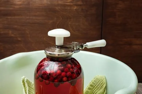 A Can Seamer. Canning cherry compote using a manual seaming machine to seal a Stock Photos