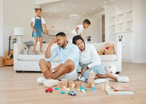 Can we get some rest. a young couple looking stressed at home while their kids Stock Photos