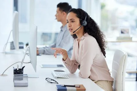 Can you please repeat that. a young call centre agent working on a computer in Stock Photos