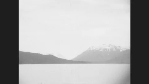 Canada 1930s: Snow-Covered Mountains Across A Lake. A Union Jack Flag. Stock Footage