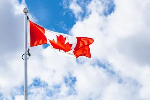 Canada flag flying on blue cloudy sky. Canadian Maple Leaf national Flag Stock Photos