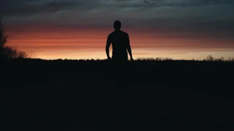 Canada - A man walking in the dark landscape towards the sunset - Wide shot Stock Footage 130243354