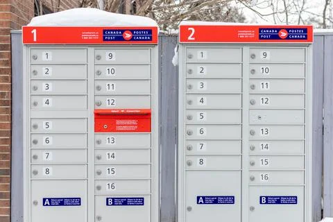 Canada Post mailboxes with red sign in English and French near house in winte Stock Photos