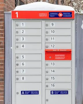 Canada Post mailboxes with red sign in English and French near house in winte Stock Photos