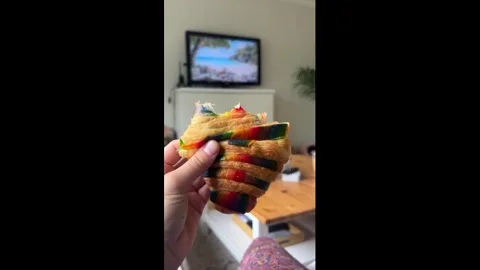 Canada: Sneaky kitten steals bite of rainbow croissant before pride parad... Stock Footage 336797693