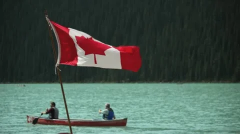 Canadian flag and canoeists on lake louise, banff alberta Stock Footage