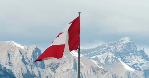 Canadian Flag Blowing in the Wind with the Rocky Mountains in the Background Stock Footage