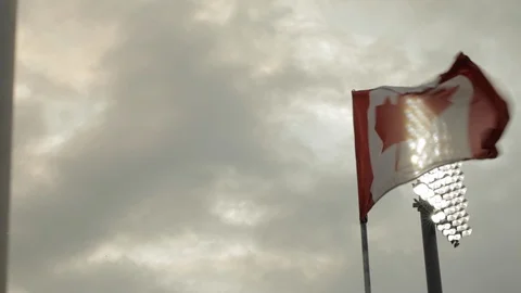 Canadian Flag Flapping in the Wind in Front of Stadium Light Stock Footage 112949051