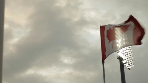 Canadian Flag Flapping in the Wind in Front of Stadium Light Stock Footage 112949444