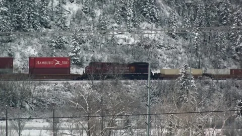 A Canadian Pacific (CP) train led by a red locomotive pulls container cars Stock Footage 322188816