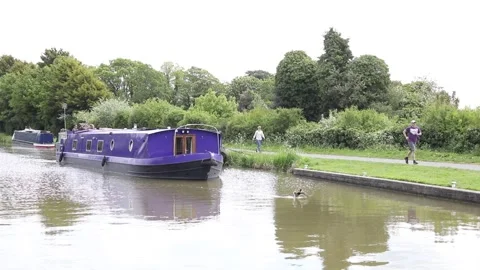 Canal boat moving alongside walkers and cyclists on the tow path Stock Footage 132065053