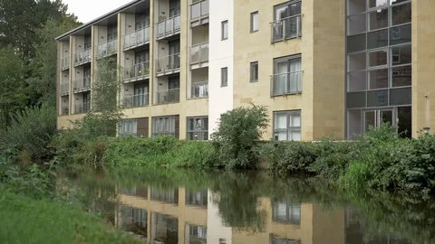 A canal side tilt shot from the reflection of a building to the building itself Video stock 117426979