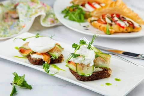Canapes on black bread with cheese, red fish, herbs and cucumber side view Stock Photos