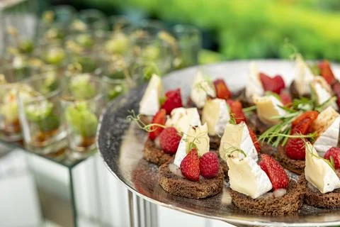 Canapes with brie cheese, raspberry and strawberries. The concept of restaurant Stock Photos