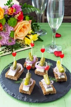 Canapes with rye bread, herring and pickles on a festive table. Stock Photos