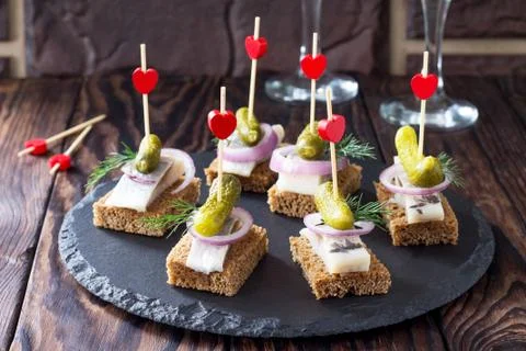Canapes with rye bread, herring and pickles on a festive table. Foto stock